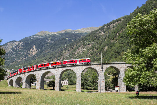 Brusio, Switzerland: 26 August 2018 - Bernina Express is going through the circular viaduct in Swiss Alps mountain, Brusio, It is 110 metres long, a radius of 70 metres, a longitudinal slope of 7%.