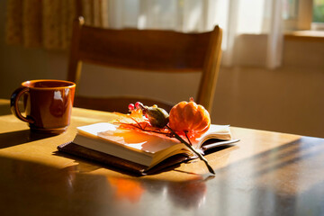 日差しが当たる机の上のコーヒーカップと本