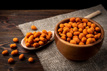 Paprika roasted peanuts on dark wooden background. Delicious snack peanut.