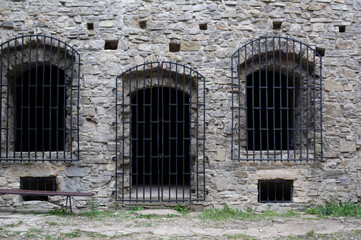 Fototapeta na wymiar Historic jail, prison and jailhouse - old, historical and antique wall made of stone. Windows and doors with iron bars and grating. 