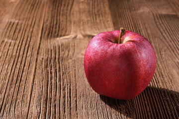 One red apple lies on a wooden table.