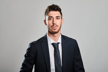 Young man portrait wearing a dark blue suit and a dark blue tie with red and light blue dots looking at camera