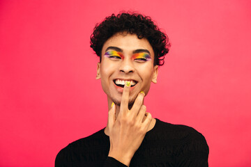 Smiling gay man with rainbow eye shadow and smiley nailpaint - obrazy, fototapety, plakaty