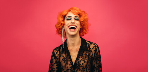 LGBTQ drag queen laughing on pink background