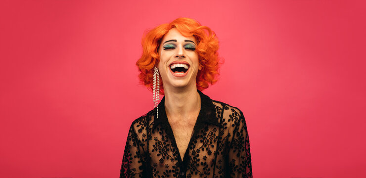 LGBTQ drag queen laughing on pink background