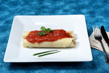 beef pancakes with a delicious red tomato sauce served in a white dish on a blue background