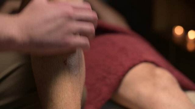 Close-up male masseur massages the calf muscle to a male athlete in a professional massage salon. Sports massage in 4k