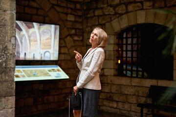 woman in the museum uses the touchscreen monitor electronic guide, the concept of modern education