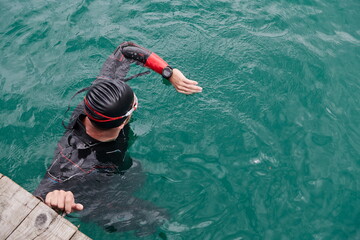 triathlon athlete swimming on lake setting smartwatch