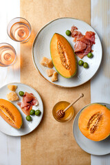 Fresh cantaloupe melon with ham, cheese and green olives with glass of rose wine. Traditional Spanish and Italian appetizer, antipasti snack. Top view