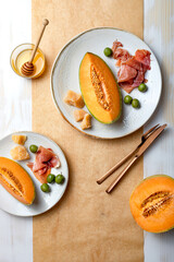 Fresh cantaloupe melon with ham, cheese and green olives. Traditional Spanish and Italian appetizer, antipasti snack. Top view