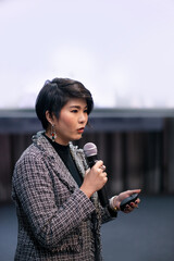 asian woman speaking over white screen in seminar