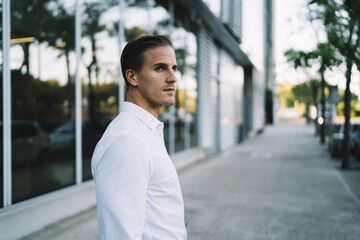 Confident young male near glass wall in street