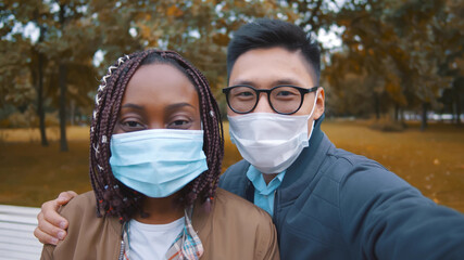 Young diverse people taking selfie outdoor wearing protective face masks