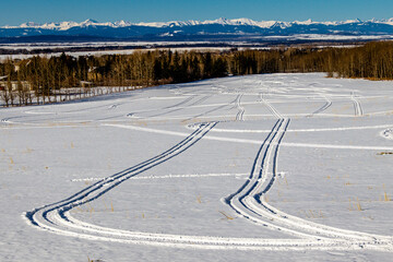 Snowmobile tracks in the snow. Springbank, Alberta, Canada
