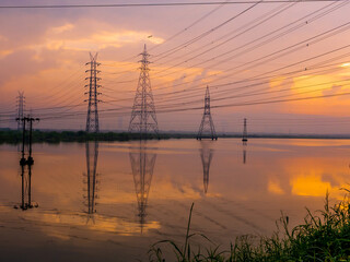 High-voltage power lines at Sunrise/sunset. .Saltpans in Mumbai.
