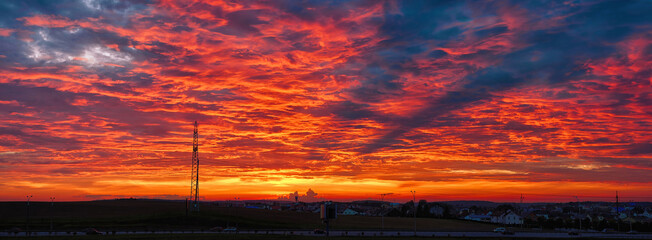 Dramatic red sunset, silhouettes of cars on the town ring road. Colorful magnificent sky background...