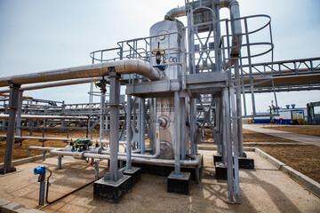 Oil refinery plant in desert sands. Heat exchanger, pipes and pipelines. Valve armature and hydrogen sulfide meter. Blue sky and sun background. Uralsk region, Kazakhstan.