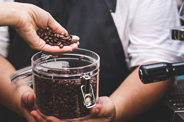 The fat man holds a jar of roasted coffee beans. Barista Cafe ingredients preparation process