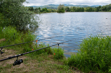 Obraz na płótnie Canvas Beautiful fish pond near Badin, Banska Bystrica, Slovakia. Fishing place. Fish pond in summer day. Fishing rods. Waiting for fish.