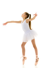 Cute little girl in a tutu and pointe shoes dancing in the studio on a white background.