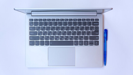 Fototapeta na wymiar Light gray Laptop and pen on a white background. Silver ultrabook top view