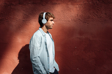Direct sun photo of a man wearing headphones being outdoor in the street.