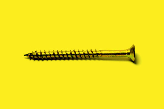 Parafuso dourado de metal com fundo amarelo