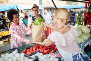 Seller woman selling fresh and organic vegetables at the green market or farmers market stall. ...