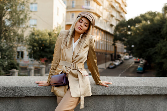 Outdoor image of  elegant european woman walking in  autumn  city . Beige  cap and jacket. stylish accessories. .