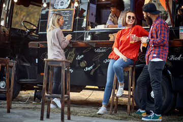 Friends drinking beer in front of food truck; Urban lifestyle concept