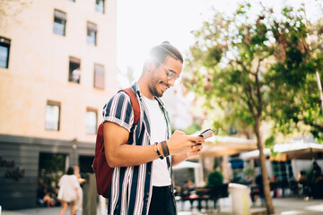 Cheerful ethnic guy messaging on smartphone