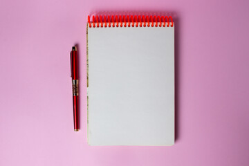 Notepad and pen on a pink background. A clean notepad. There is space for an inscription or logo on the notebook