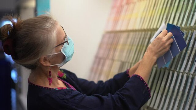 Closeup of woman wearing face mask looking at paint chips in a hardware store. Concept of cornonavirus shopping experience.