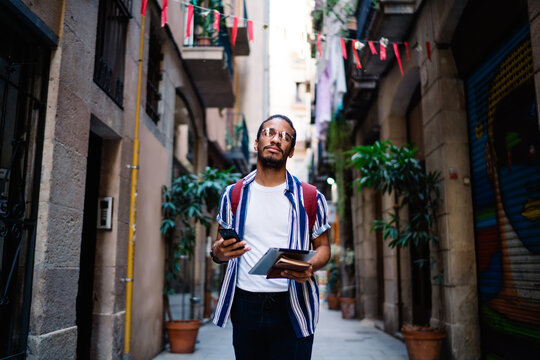 Serious Ethnic Guy Walking On Street In Old Town