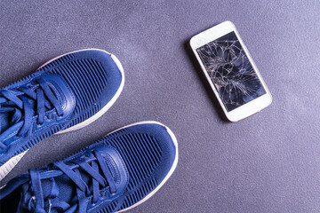 Fitness equipment with sneakers and smartphone on gray background, top view. Copy space.