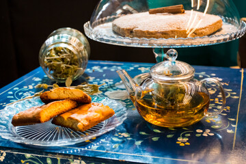 The tasty homemade cinnamon cake with sugar, accompanied by a cup of fresh flower and herb arabic tea with chocolate and some Tasty and healthy almond cookies, rich in vitamins. copy space.
