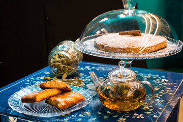 The tasty homemade cinnamon cake with sugar, accompanied by a cup of fresh flower and herb arabic tea with chocolate and some Tasty and healthy almond cookies, rich in vitamins. copy space.