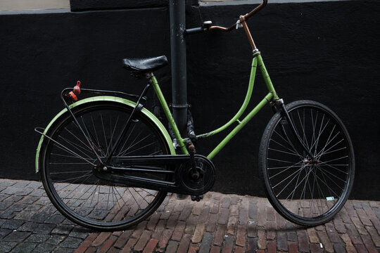 A plain green Dutch ladies bike against a black background 