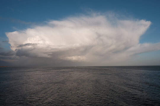 Large Cumulonimbus capillatus clouds on the horizon over the sea