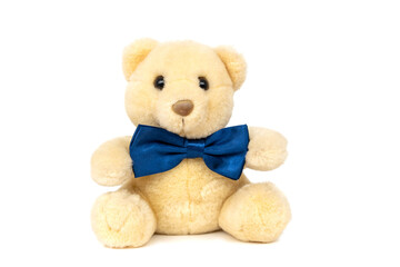 Cute funny fluffy yellow teddy bear kids favourite stuffed toy with small black plastic eyes and dark blue satin bow tie sitting isolated on white background.