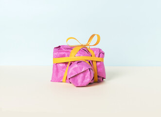 Photo camera wrapped in magenta gift paper and yellow ribbon
