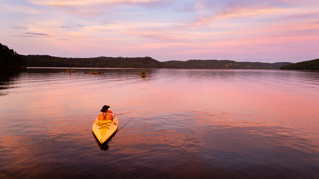 Back view of a woman fishing from a kayak on the Temiscamingue lake, Canada