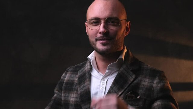 Portrait of a handsome businessman in stylish clothes put up his glasses in dark studio