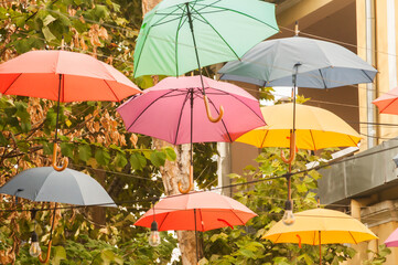 Fototapeta na wymiar Umbrellas in different colors hanging over city street