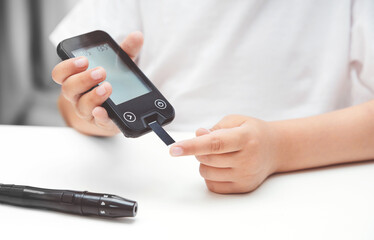 Young boy using glucometer, children diabetes