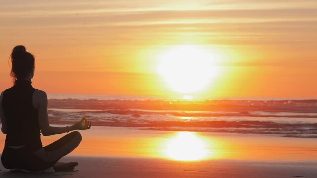 Silhouette of slim woman on the beach at sunset, Practice of yoga