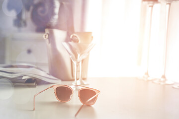 Glasses on the table in the light of the moody sun and the attributes of a woman