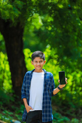 technology and people concept - smiling teenage boy in blue shirt showing smartphone with blank screen