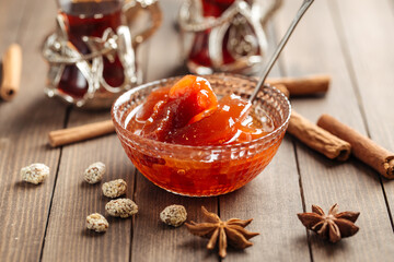 Quince jam in a glass bowl on wooden background